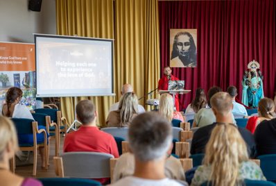 A lecture in the ashram hall with a portrait of the founder